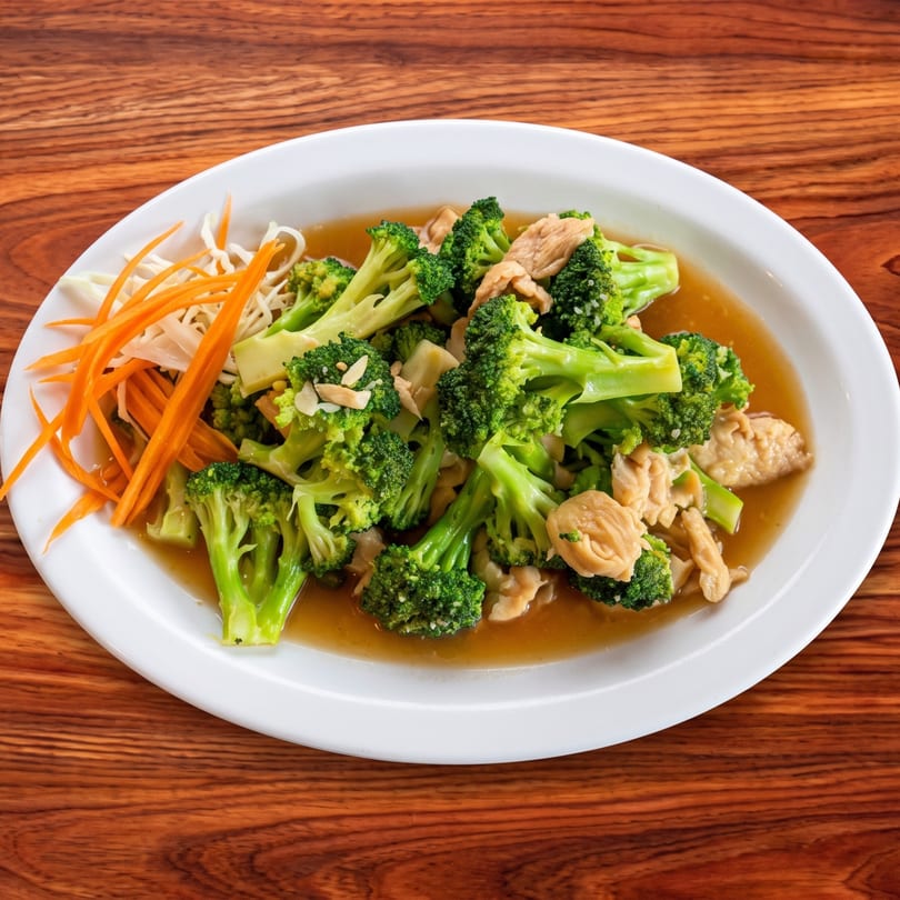 Stir-fried chicken and broccoli in a savory sauce, garnished with shredded carrots and cabbage.